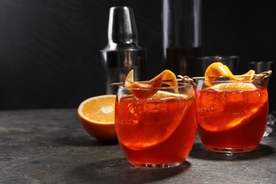 Aperol spritz cocktail, ice cubes and orange slices in glasses on grey textured table, space for text