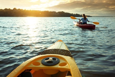 Photo of Woman kayaking on river at sunset, view from other boat. Summer activity