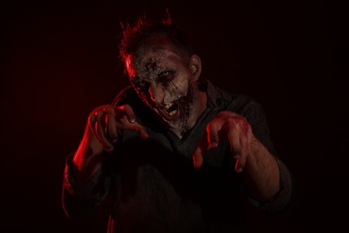 Photo of Scary zombie on dark background. Halloween monster