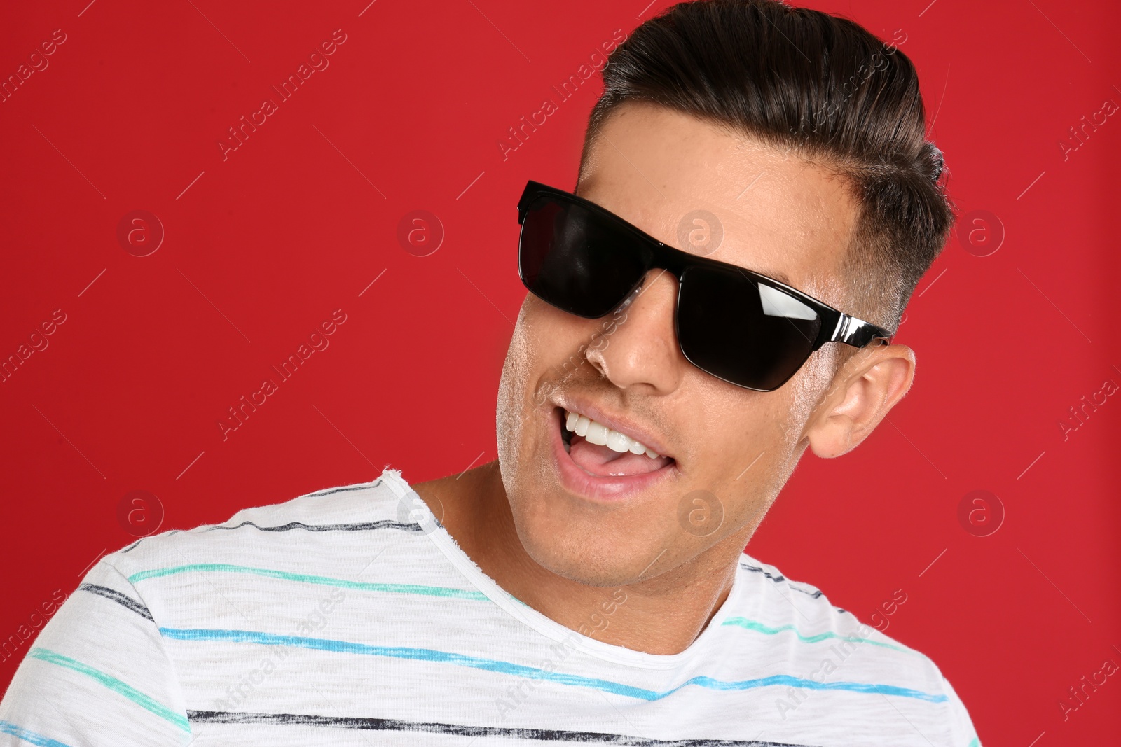 Photo of Handsome man wearing sunglasses on red background, closeup