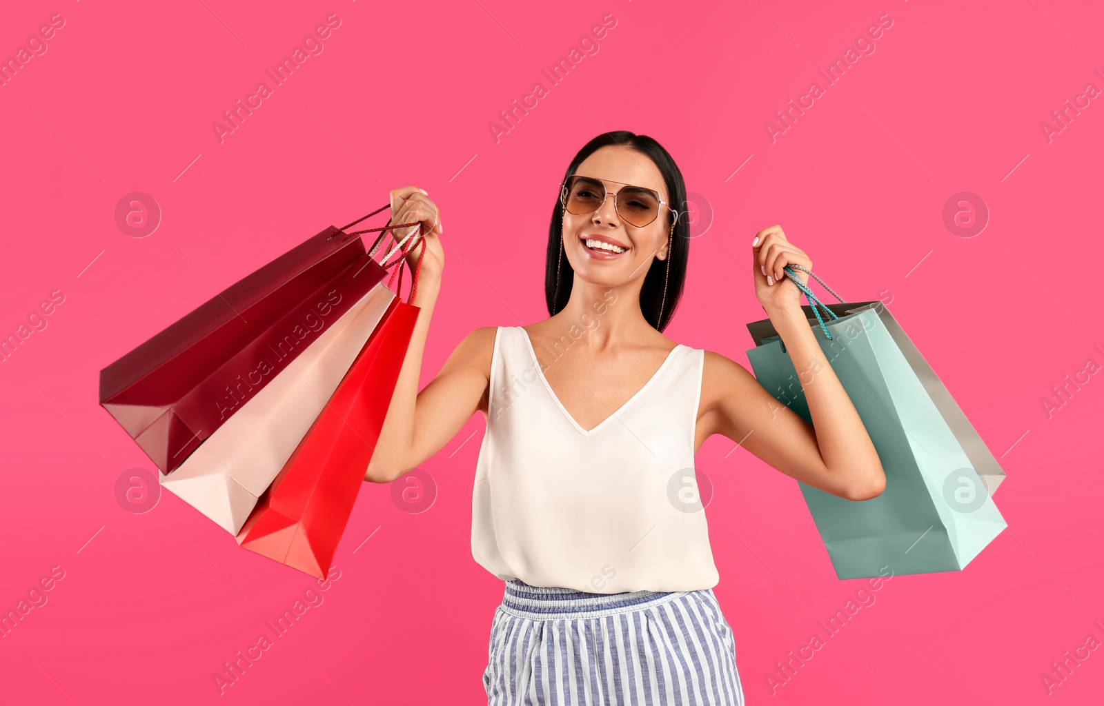 Photo of Beautiful young woman with paper shopping bags on pink background