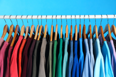 Colorful clothes on hangers against light blue background