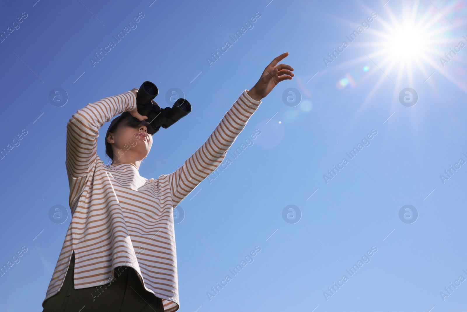 Photo of Woman looking through binoculars outdoors on sunny day, low angle view