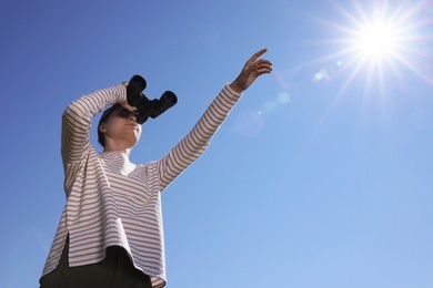 Photo of Woman looking through binoculars outdoors on sunny day, low angle view