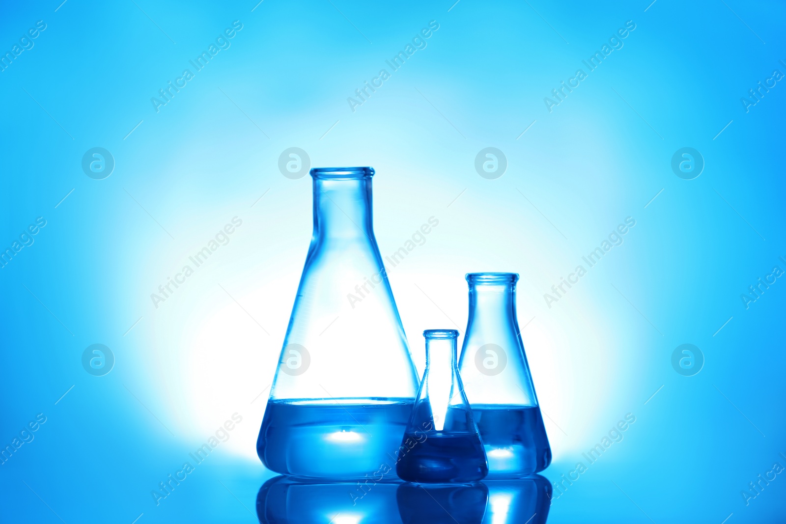 Photo of Laboratory glassware with liquid on color background. Solution chemistry