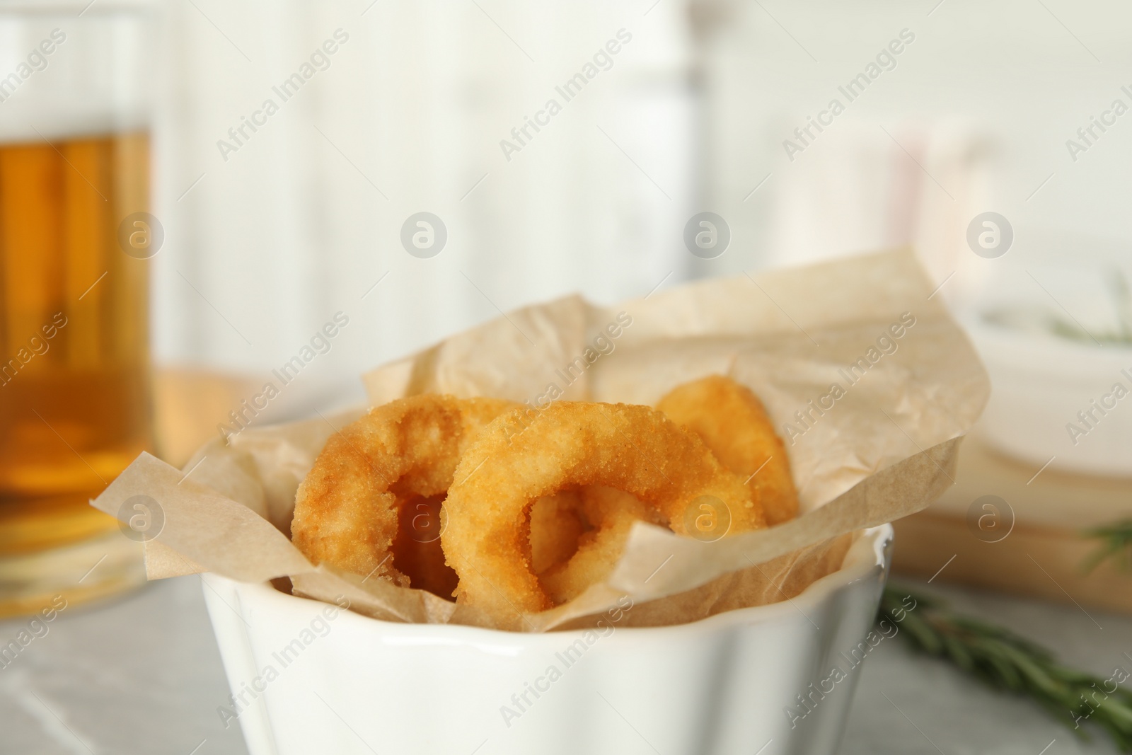 Photo of Delicious crunchy fried onion rings in bowl on table, closeup