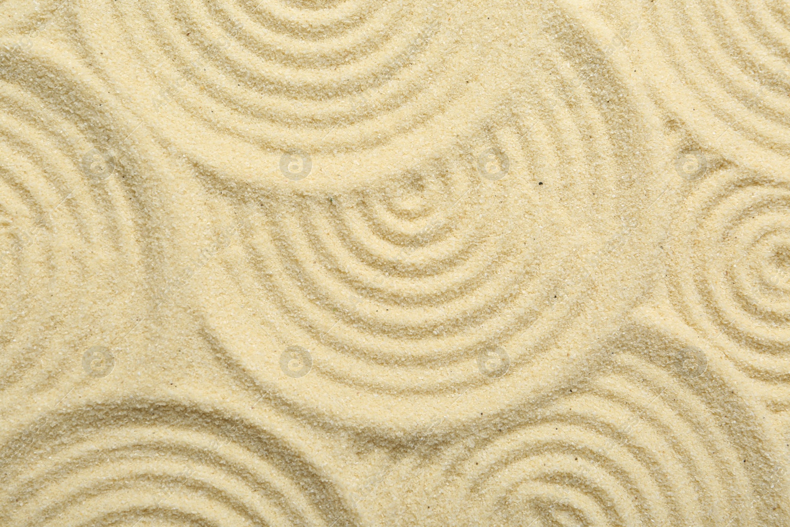 Photo of Zen rock garden. Circle patterns on beige sand, top view