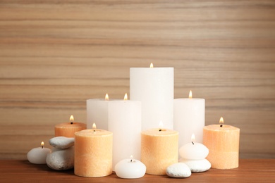 Photo of Beautiful composition with lit candles and spa stones on table