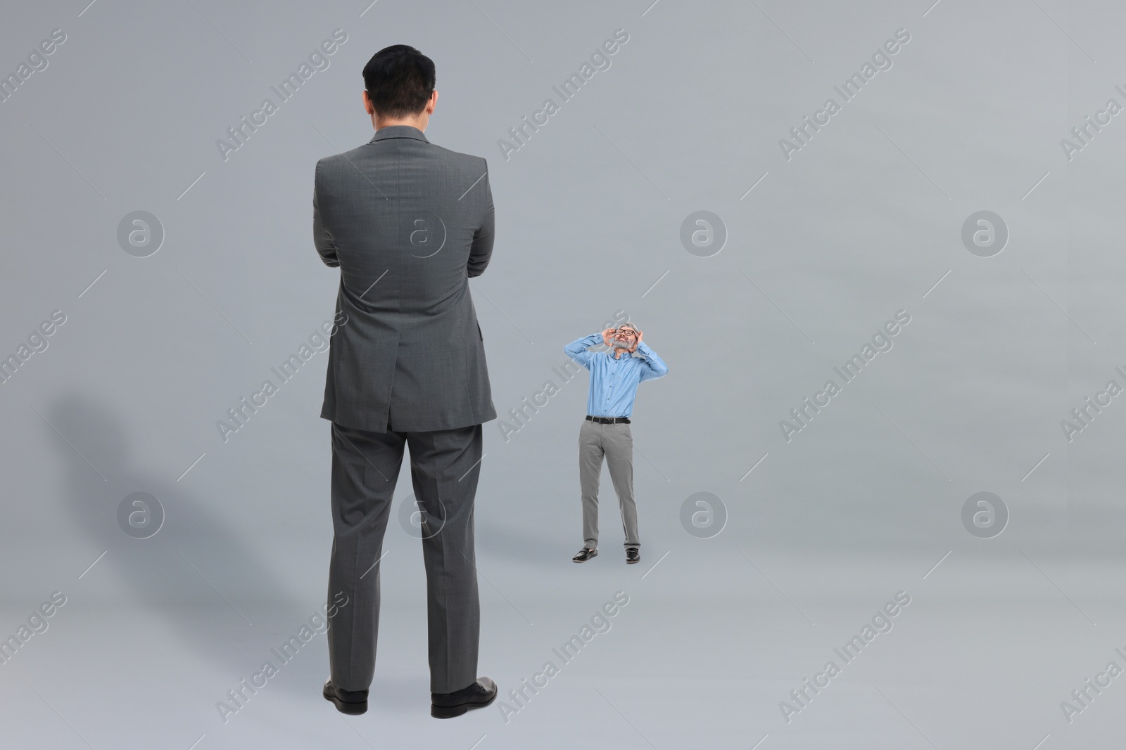Image of Small man shouting to giant boss on grey background