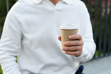 Coffee to go. Man with paper cup of drink outdoors, closeup