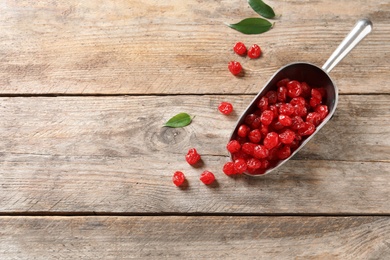 Photo of Scoop of sweet cherries on wooden background, top view with space for text. Dried fruit as healthy snack