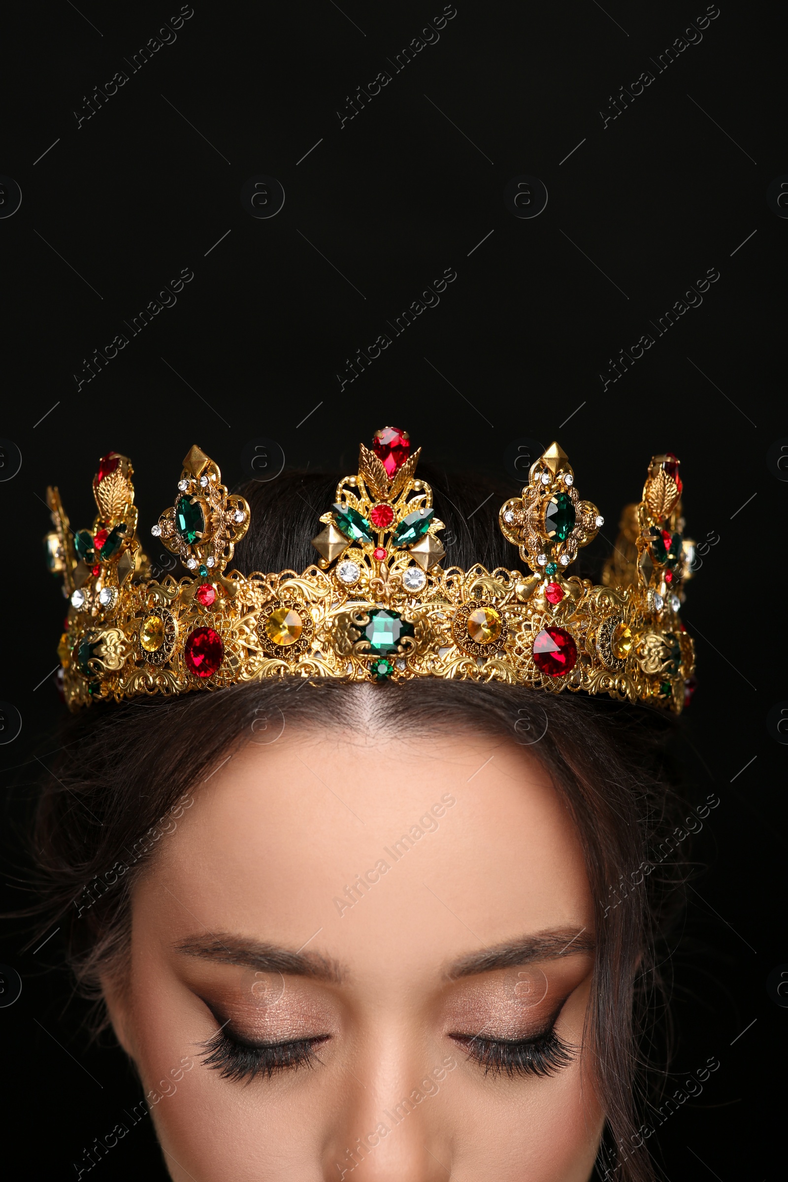 Photo of Beautiful young woman wearing luxurious crown on black background, closeup