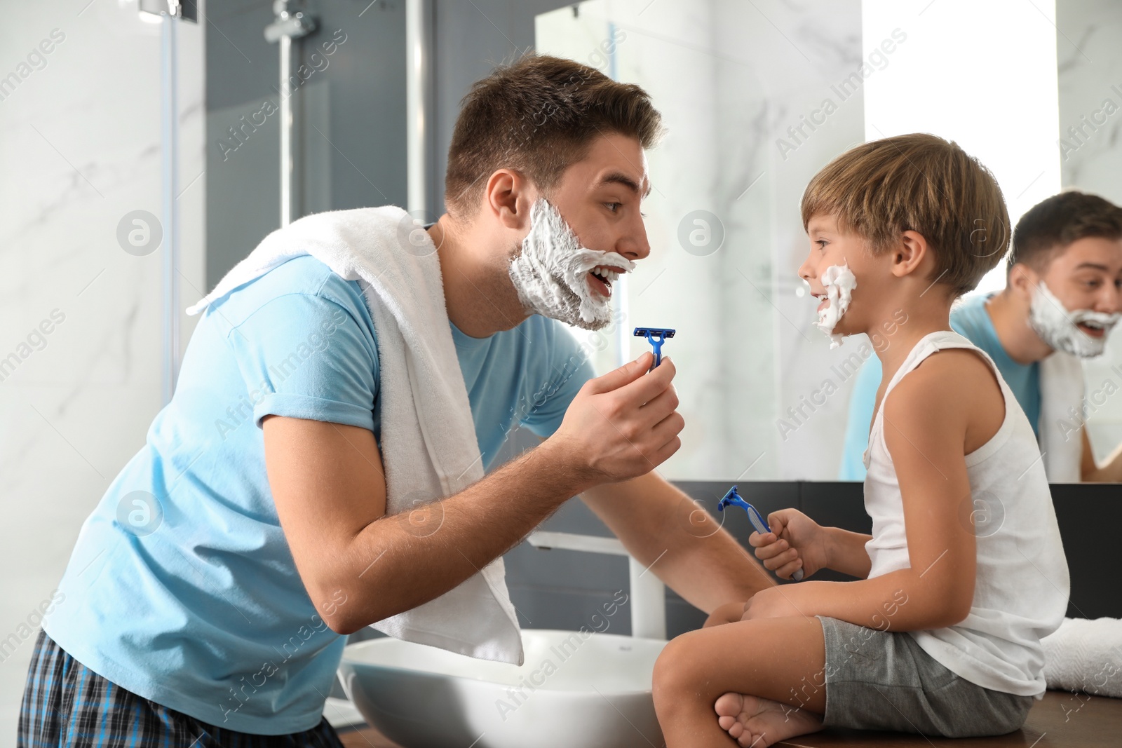 Photo of Dad and son with shaving foam on their faces in bathroom