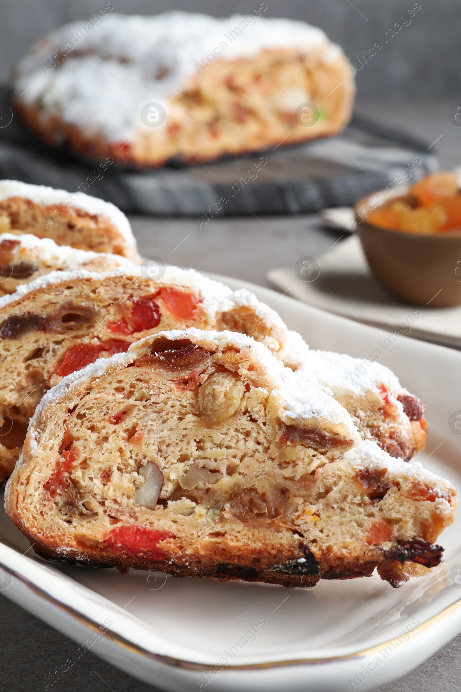 Photo of Traditional Christmas Stollen with icing sugar on grey table, closeup