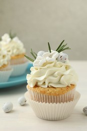 Photo of Tasty Easter cupcake with vanilla cream on light wooden table