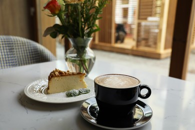 Cup of fresh coffee and dessert on table in cafeteria