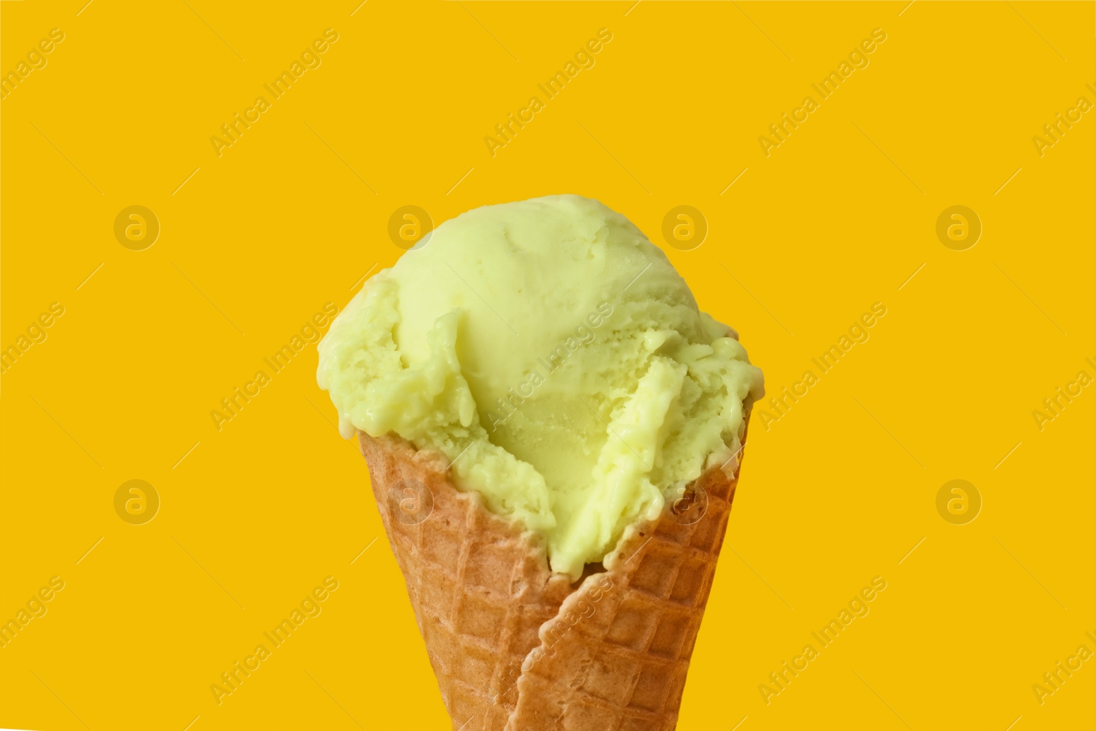 Photo of Delicious ice cream in waffle cone on yellow background, closeup