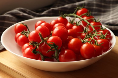 Photo of Plate of ripe whole cherry tomatoes with water drops on wooden table, closeup