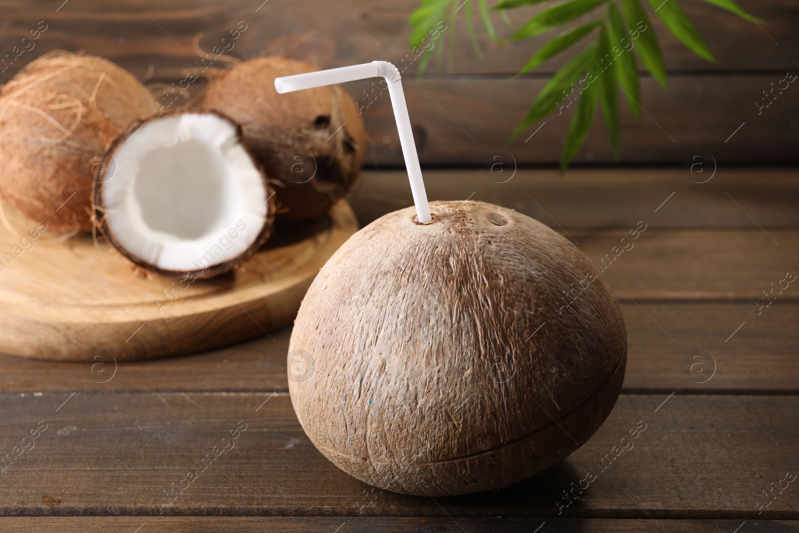 Photo of Coconut water. Fresh nut with straw on wooden table