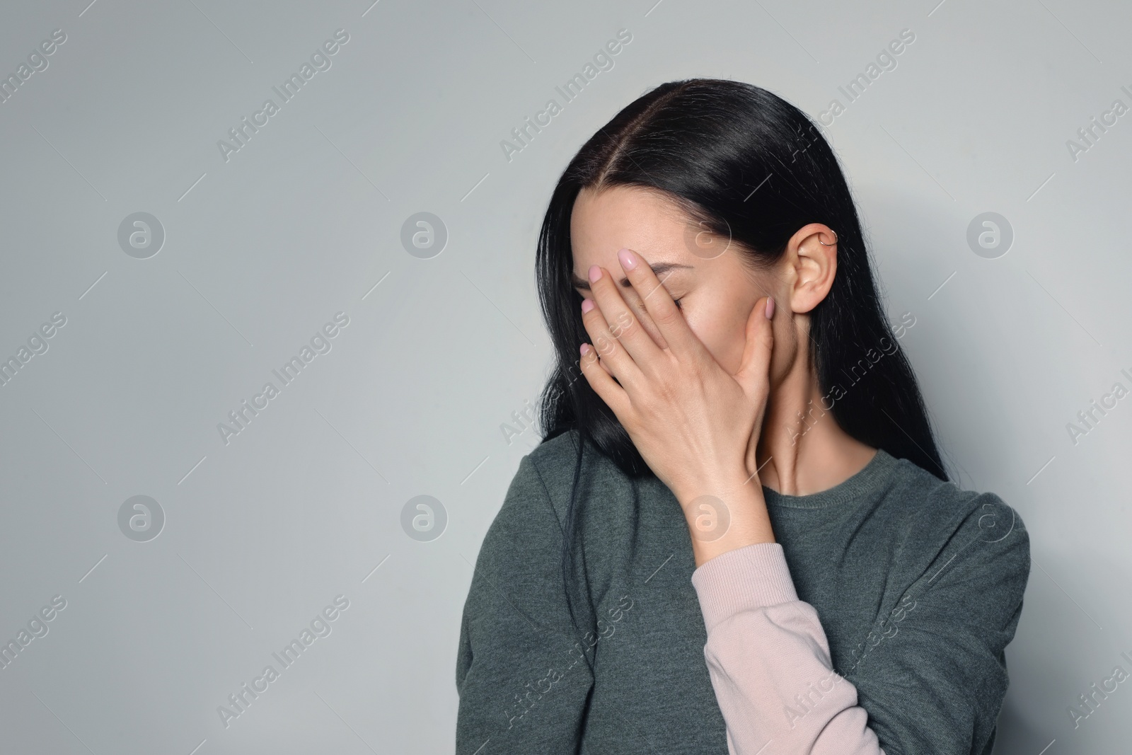 Photo of Upset young woman crying against light background. Space for text