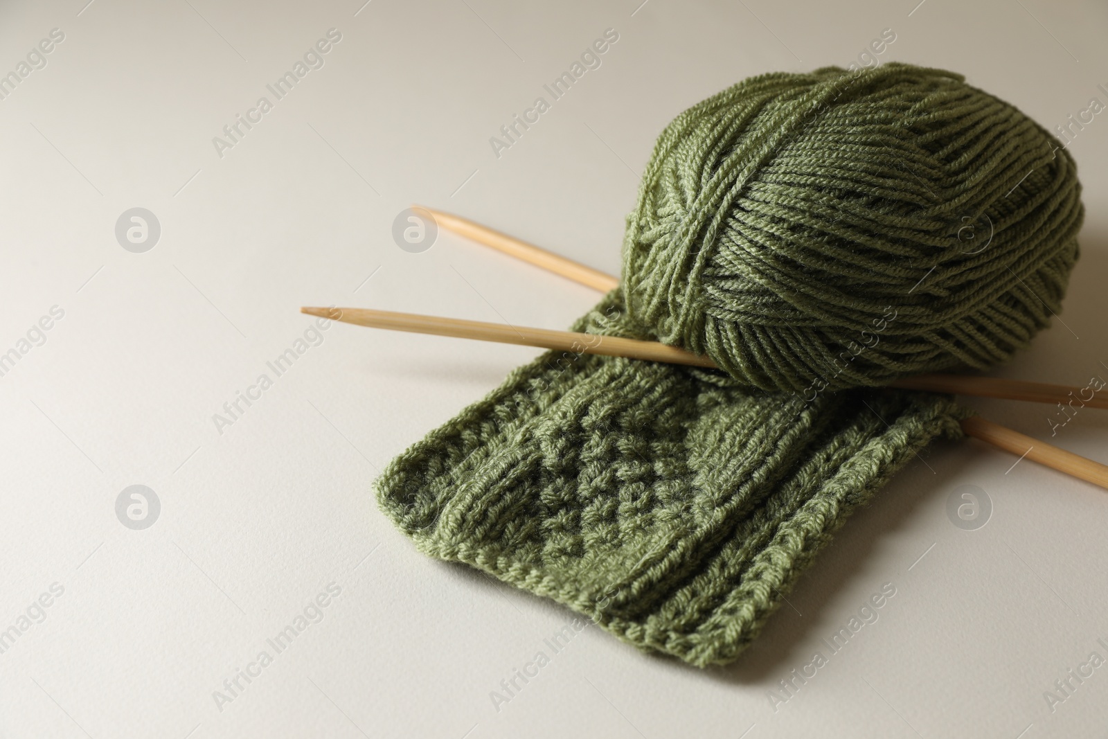 Photo of Knitting, soft yarn and needles on beige background, space for text