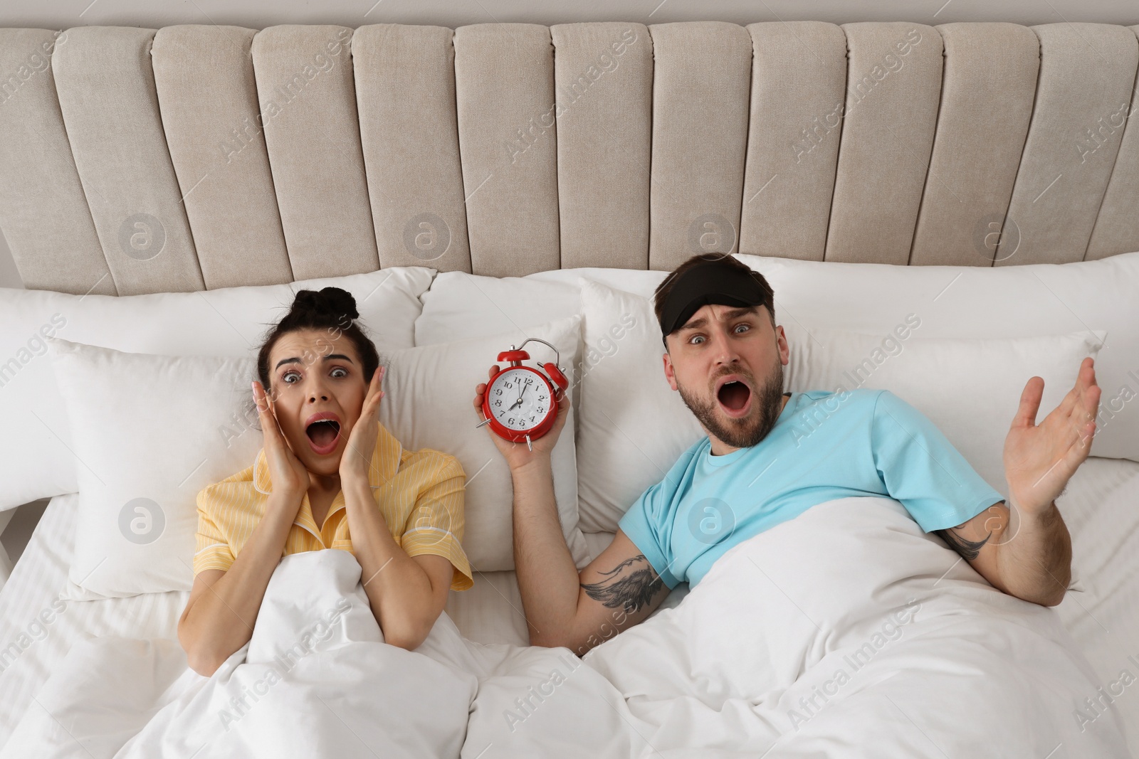 Photo of Emotional overslept couple in bed, above view. Being late concept