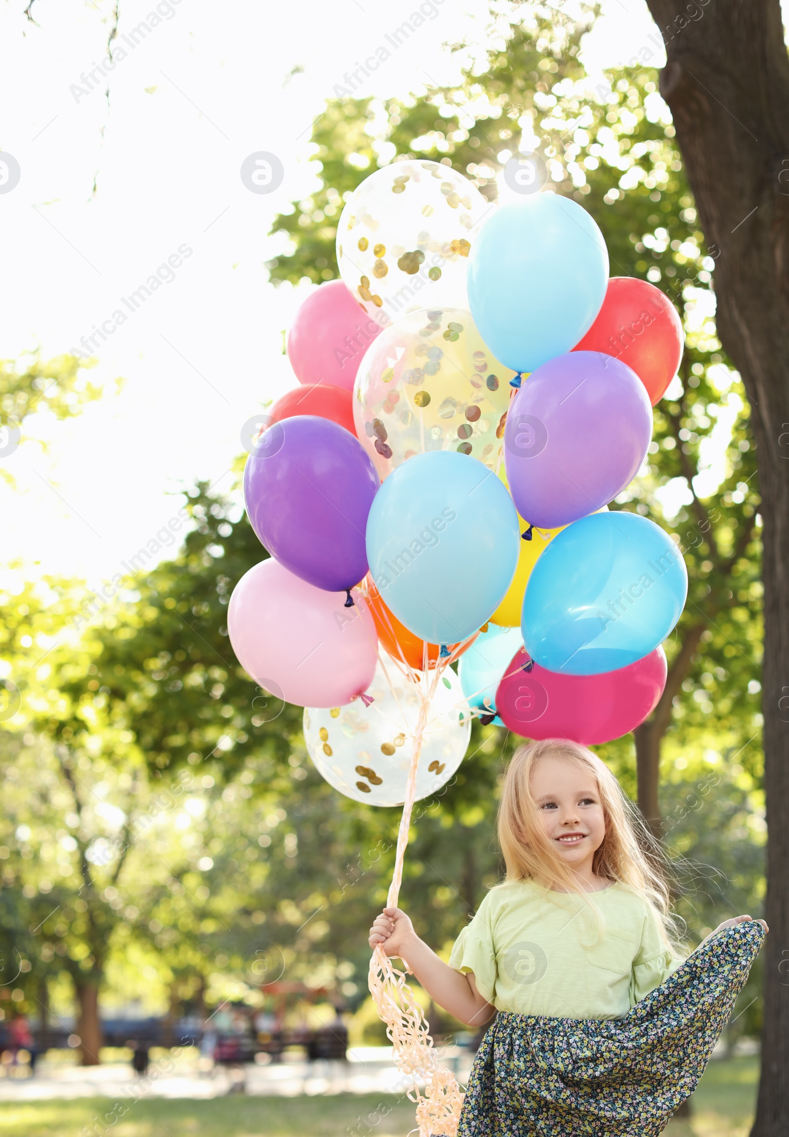 Photo of Cute little girl with colorful balloons outdoors on sunny day