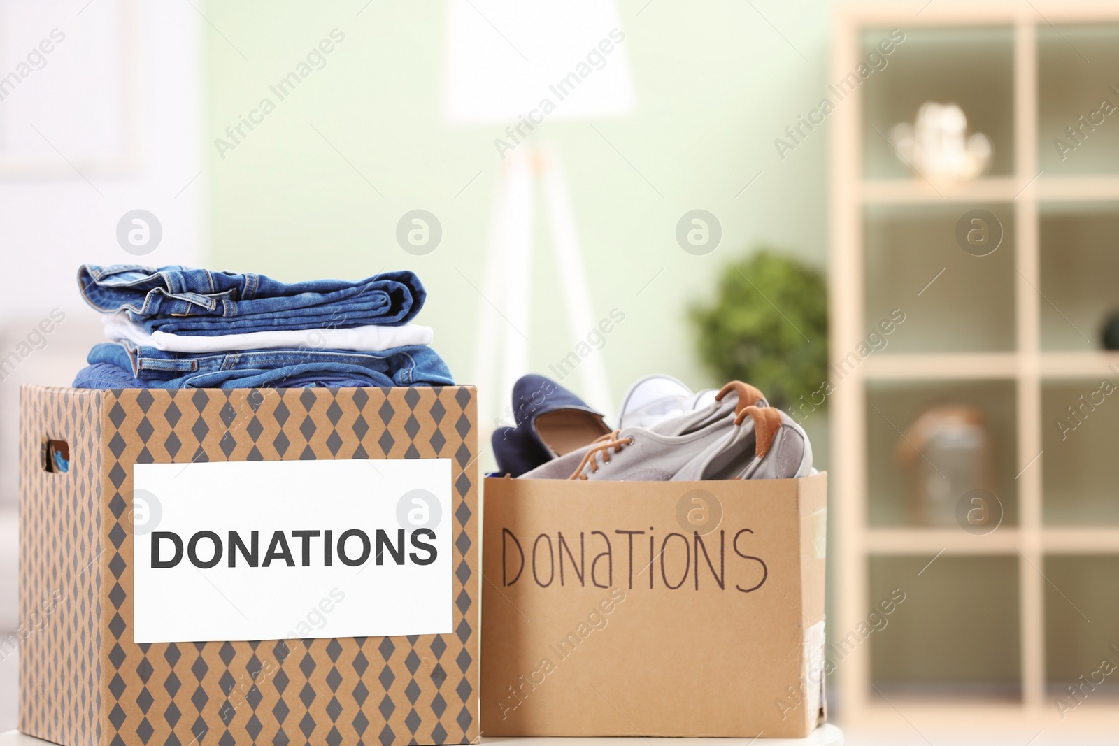 Photo of Donation boxes with clothes and shoes on table indoors