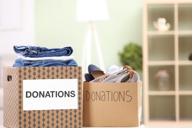 Photo of Donation boxes with clothes and shoes on table indoors