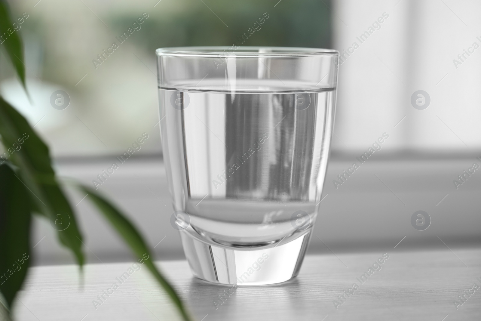 Photo of Glass of pure water on wooden table against blurred background