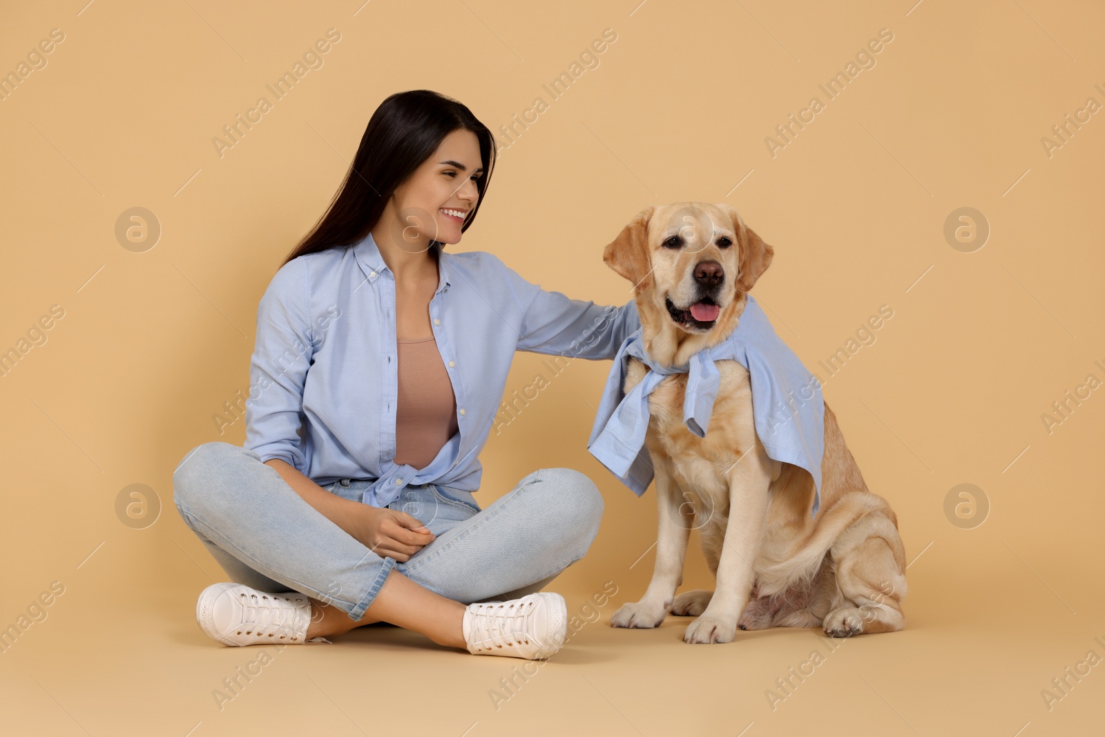 Photo of Happy woman with cute Labrador Retriever on beige background