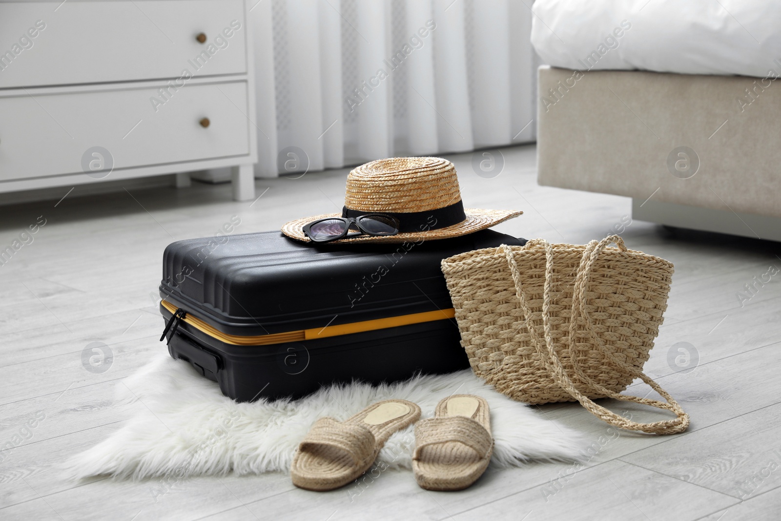 Photo of Suitcase packed for trip and summer accessories on floor indoors