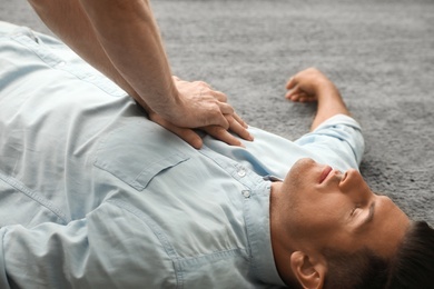 Passerby performing CPR on unconscious man indoors, closeup. First aid