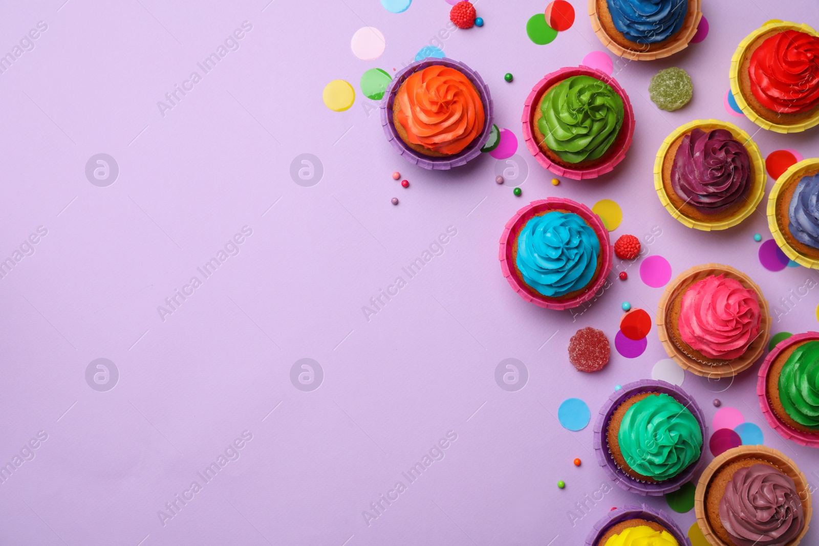 Photo of Flat lay composition with delicious colorful cupcakes on violet background. Space for text