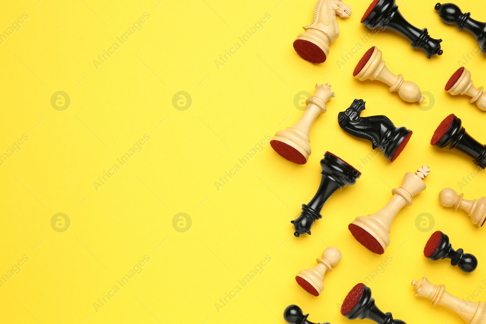 Photo of Many different chess pieces on yellow background, flat lay. Space for text