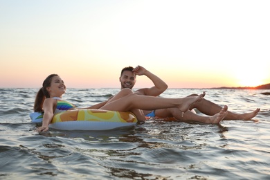 Photo of Happy young couple on inflatable rings in water