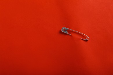 Photo of Safety pin attached on red paper, top view. Space for text