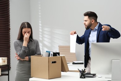 Boss dismissing young woman from work in office