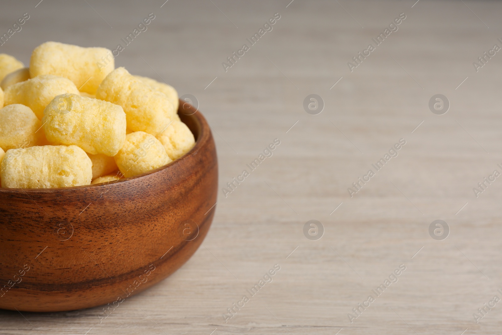 Photo of Bowl of corn sticks on wooden table, closeup. Space for text