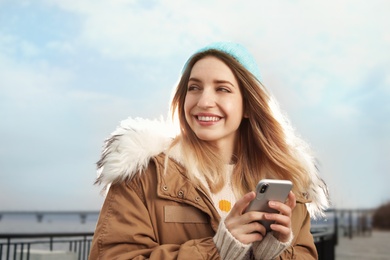 Photo of Beautiful young woman using mobile phone outdoors