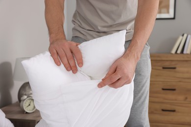Photo of Man changing pillowcase at home, closeup. Domestic chores