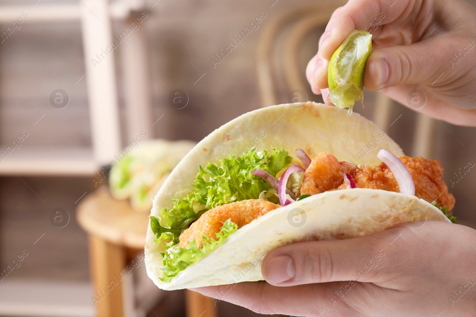 Photo of Woman squeezing lime on fish taco indoors, closeup