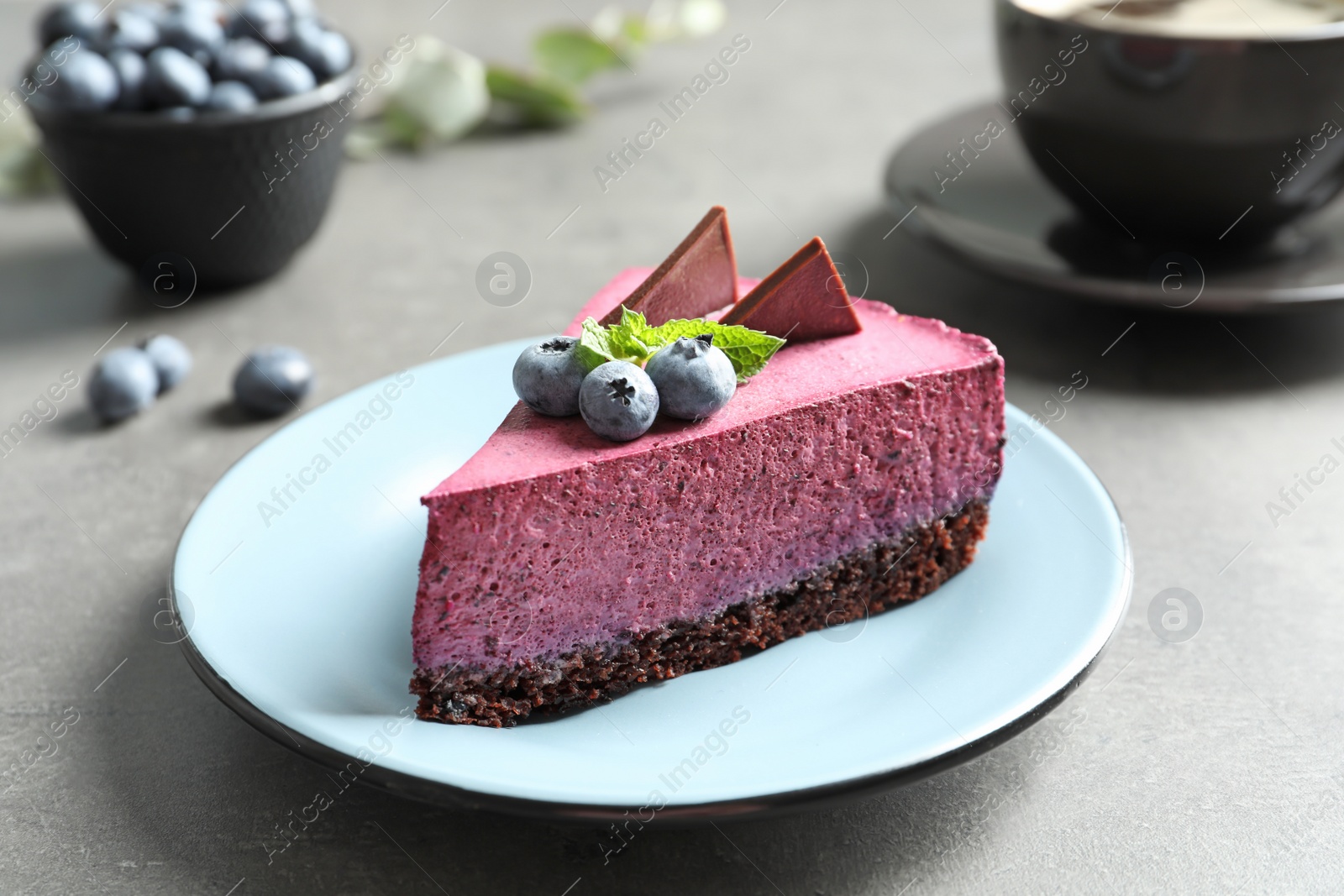 Photo of Plate with piece of tasty blueberry cake on gray table