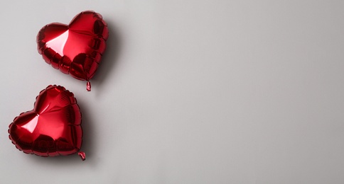 Photo of Red heart shaped balloons on grey background, space for text. Valentine's Day celebration