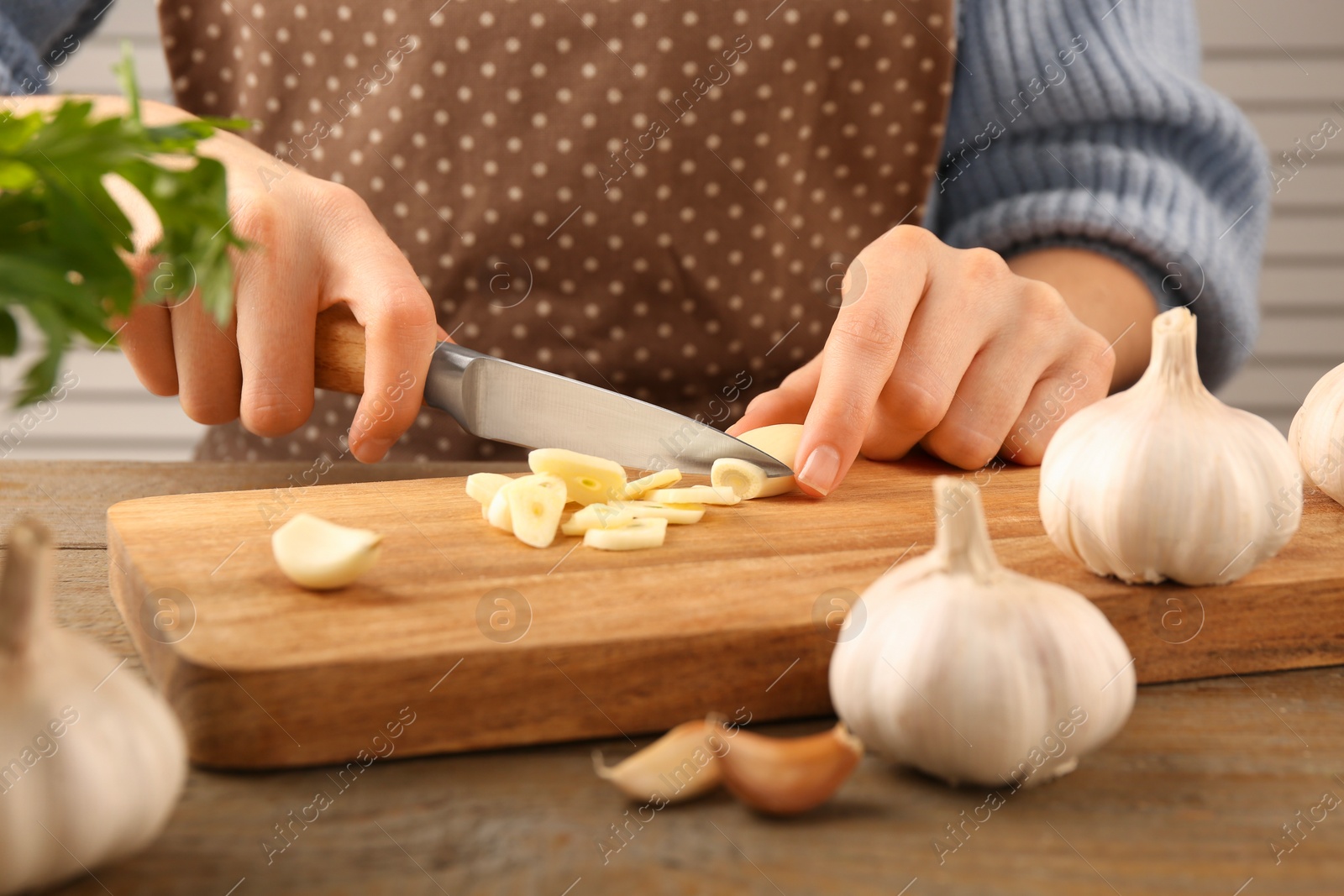 Photo of Woman cutting fresh garlic at table, closeup