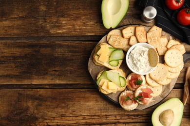Different snacks with salted crackers on wooden table, flat lay. Space for text