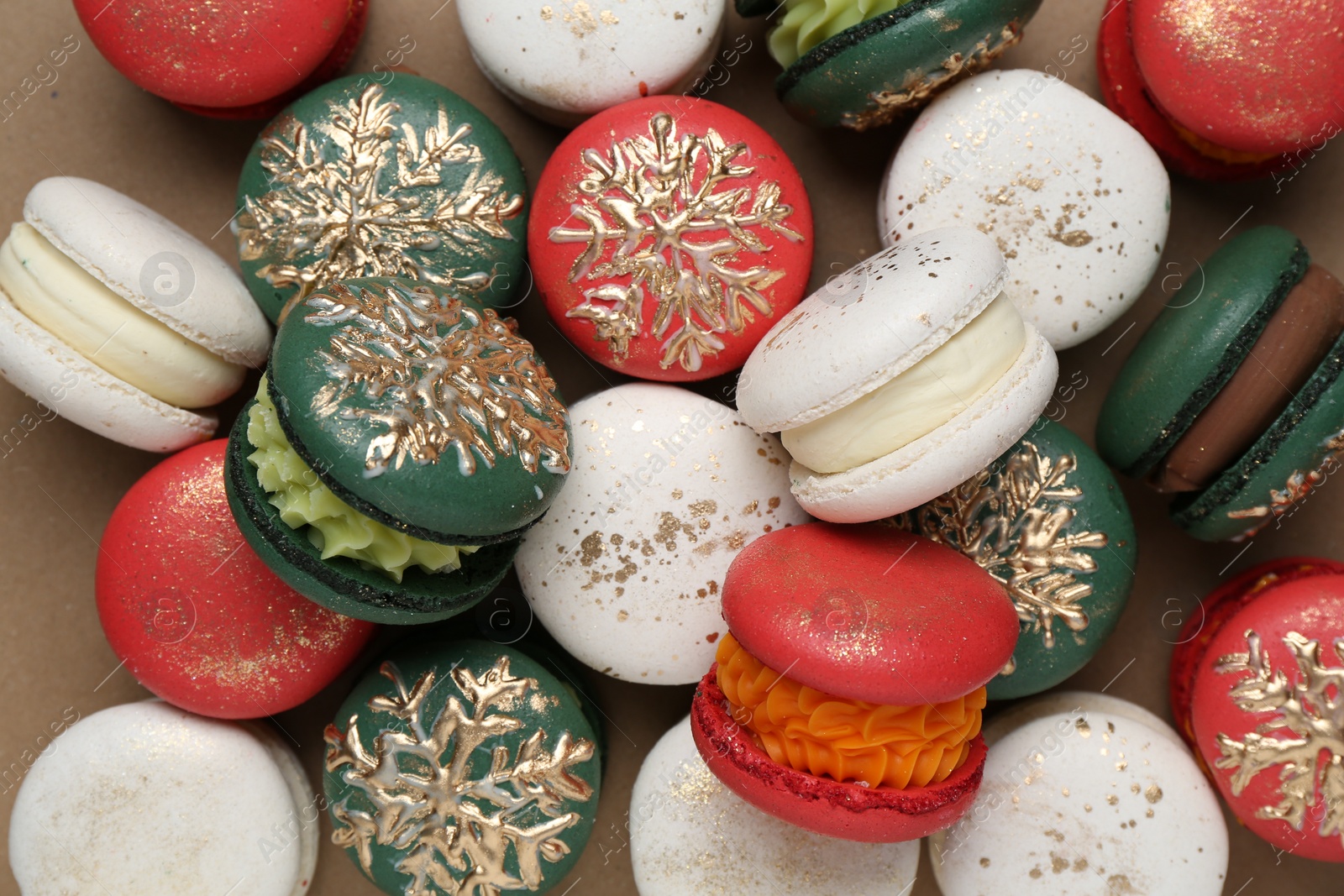 Photo of Beautifully decorated Christmas macarons on brown background, top view