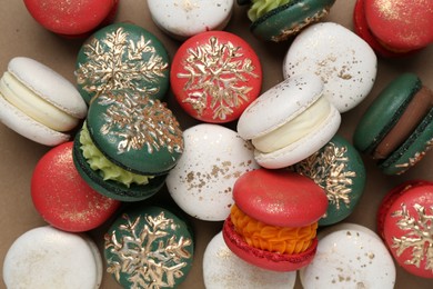 Photo of Beautifully decorated Christmas macarons on brown background, top view