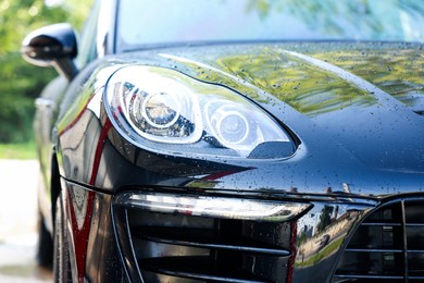 Photo of Clean auto after washing at outdoor car wash, closeup