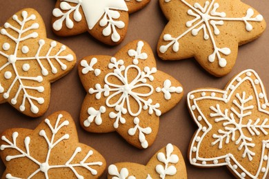 Photo of Tasty Christmas cookies with icing on brown background, flat lay